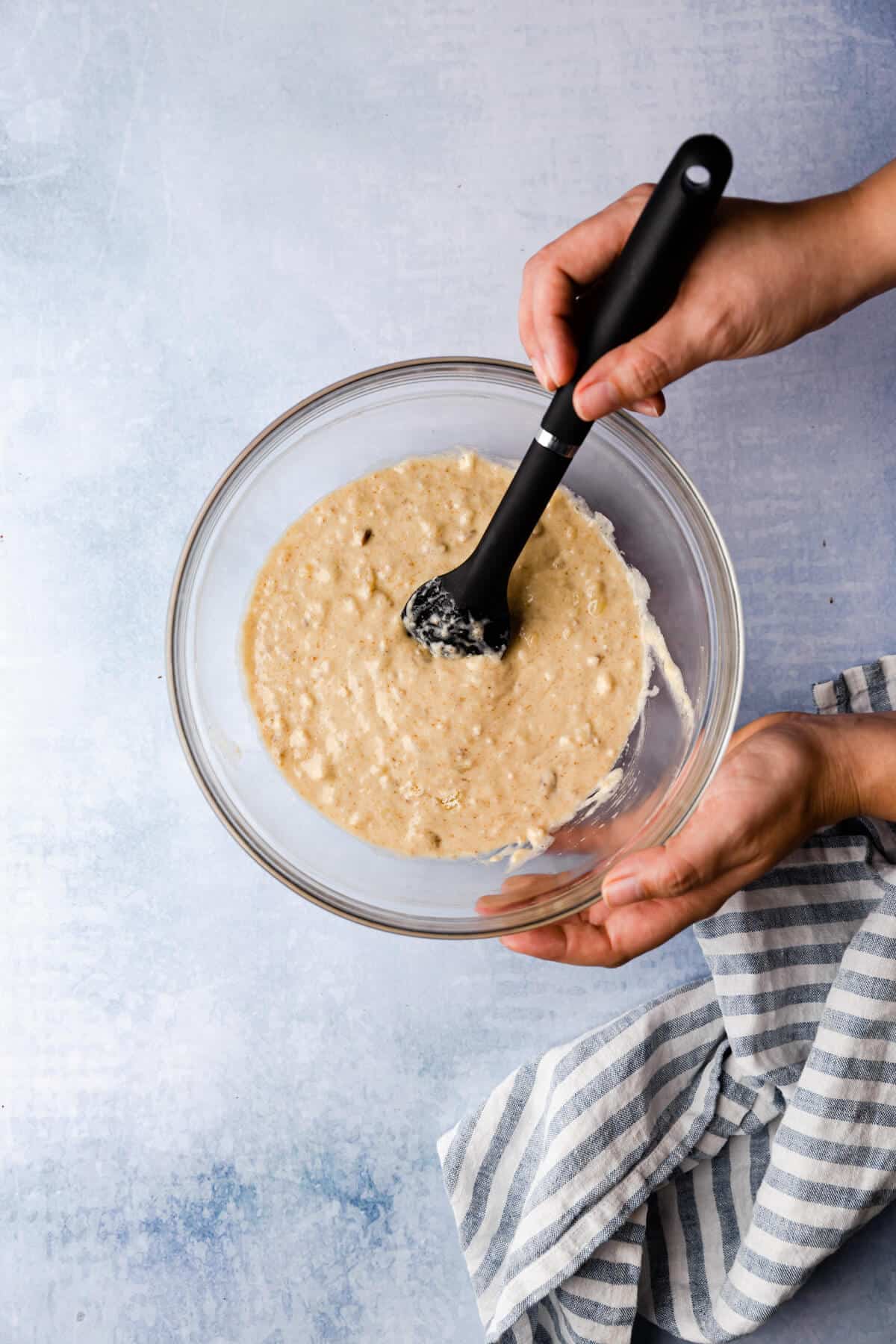 top view of a person mixing the batter in a bowl with spatula