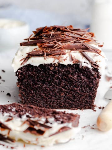 side close up photo of Guinness chocolate loaf cake topped with frosting and chocolate curls