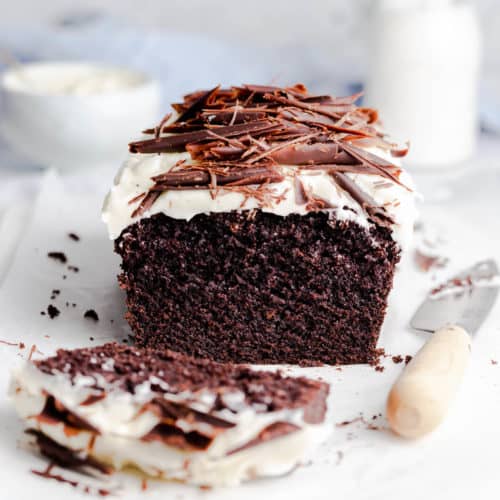 Guinness chocolate loaf cake topped with frosting and chocolate curls