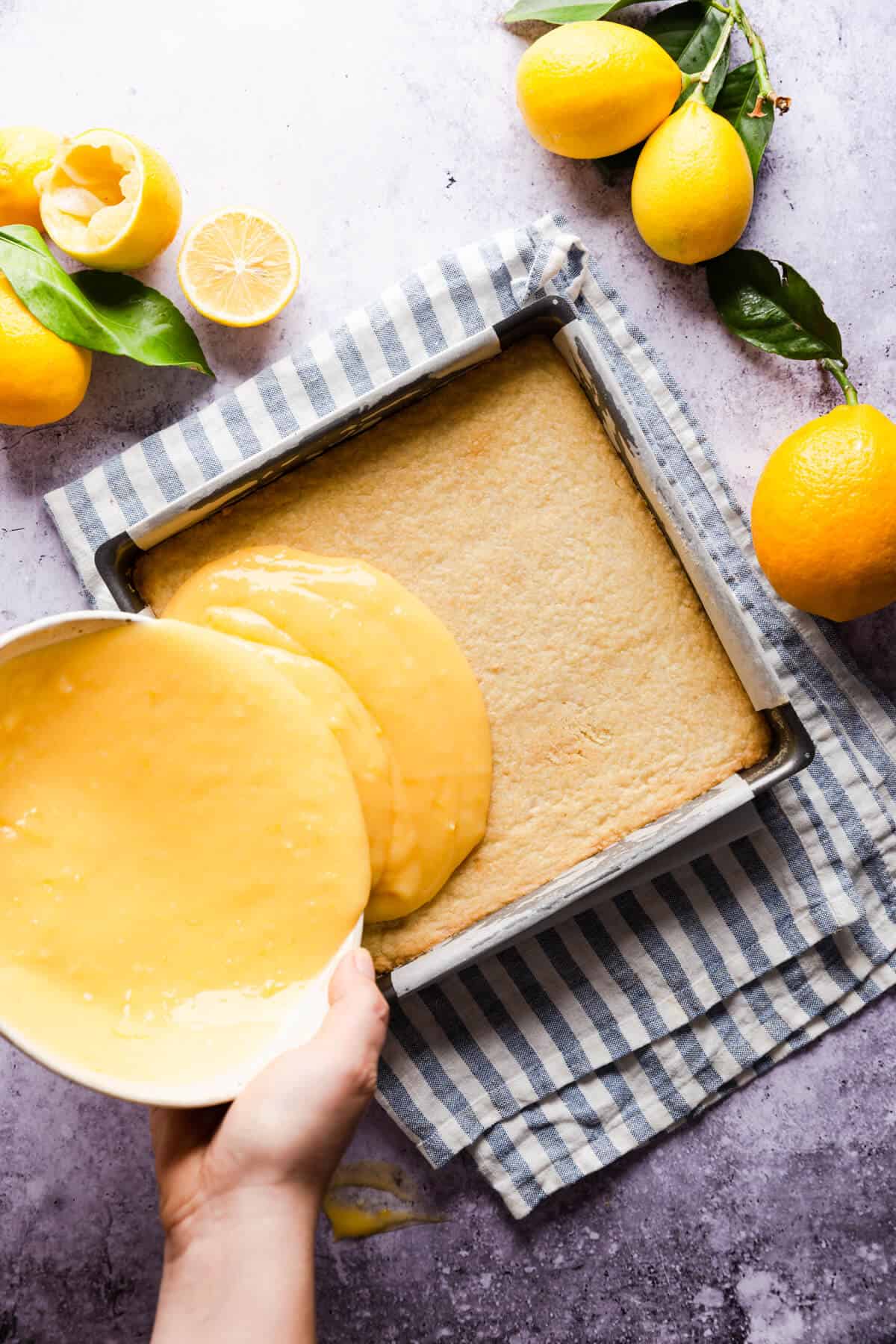 overhead shot of a person pouring the lemon curd filling on top of shortcrust base