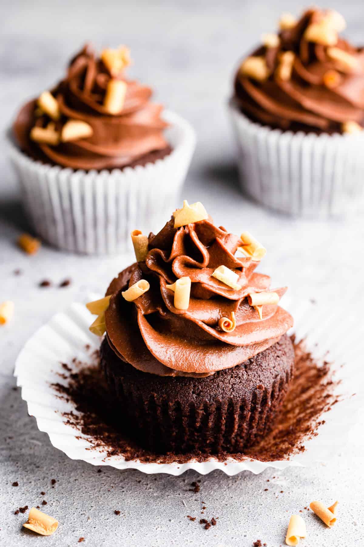close up at a chocolate cupcake with buttercream unwrapped from its paper case