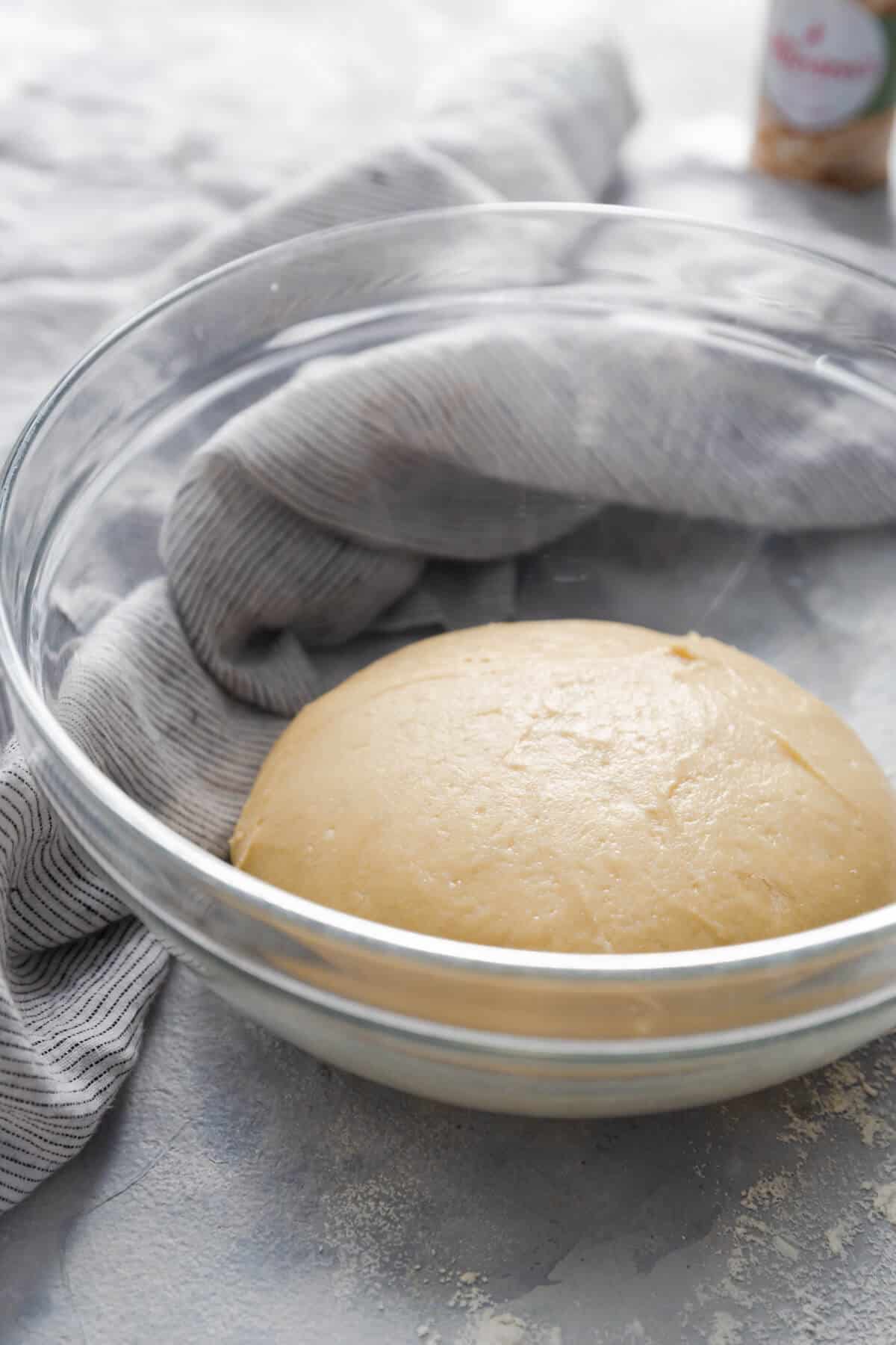 side angle close up photo of a glass bowl with dough rising inside