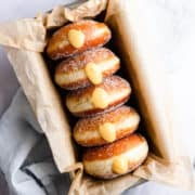 top view close up of 5 doughnuts filled with orange curd in a baking tin