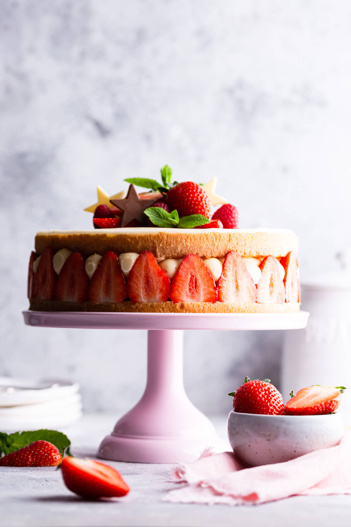 side close up of fraisier cake topped with fresh strawberries