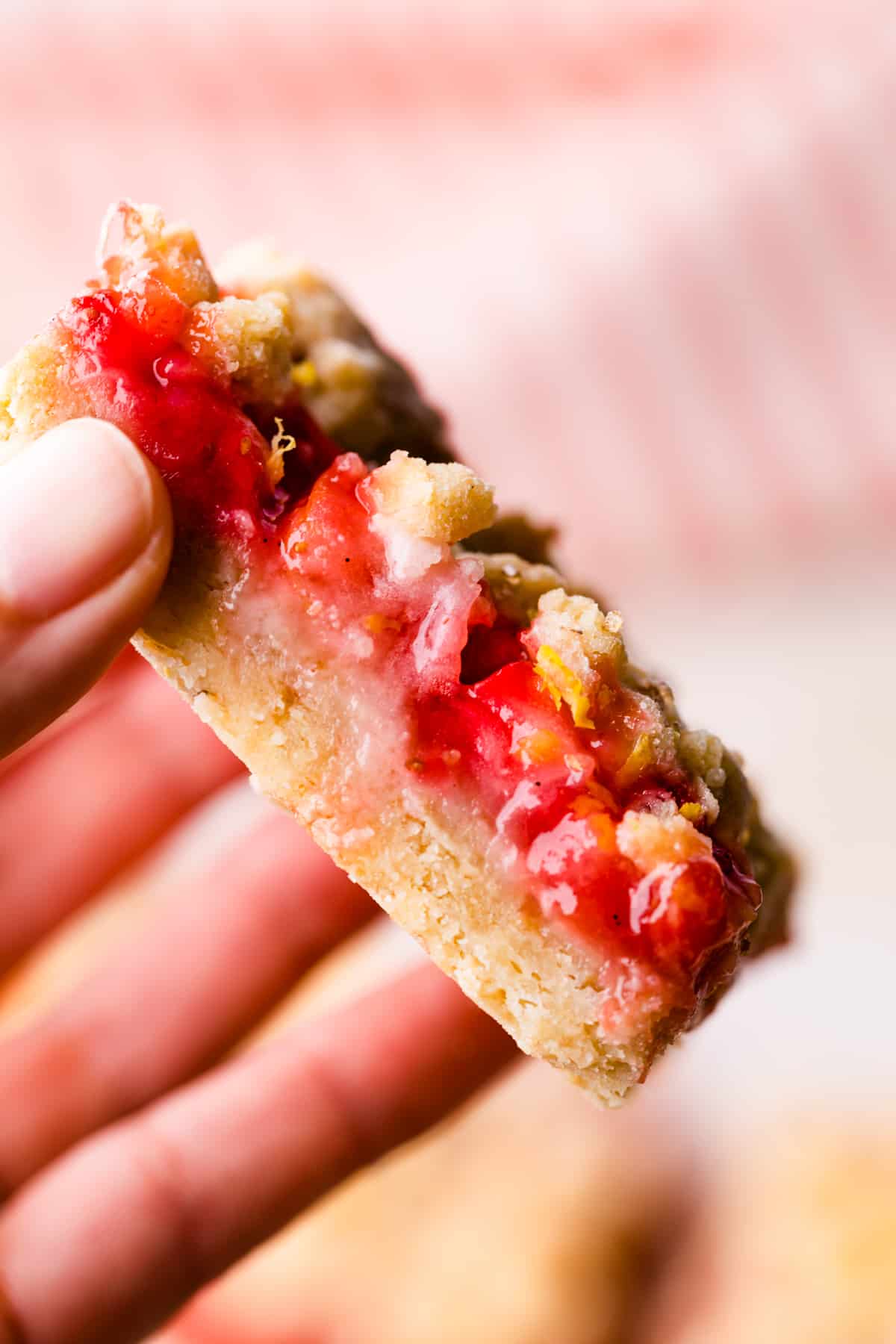 individual slice of strawberry crumble bar being held in hand.