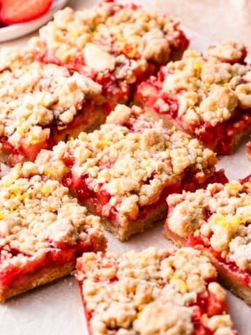 slices of crumble bars with strawberries and crumble topping dusted with icing sugar and lemon zest.