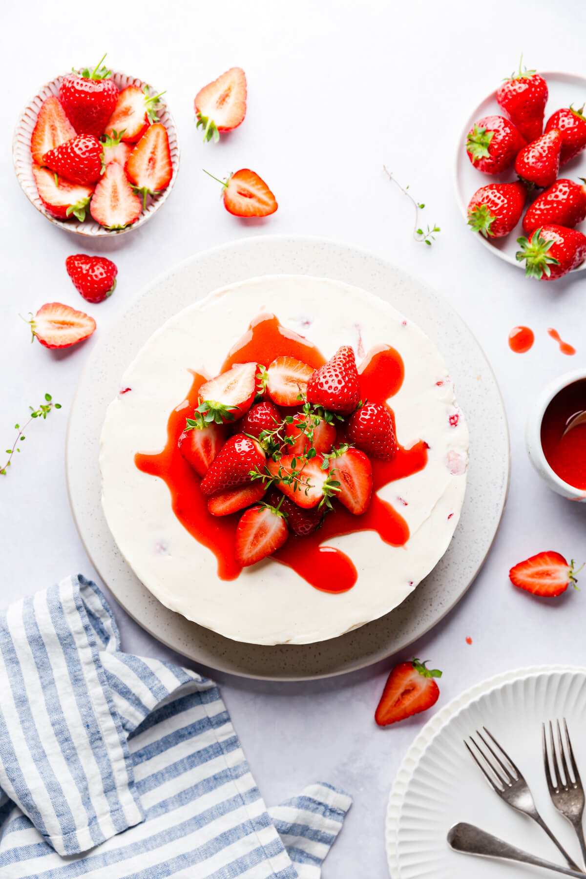 top view of a strawberry white chocolate cheesecake topped with sauce and fresh strawberries