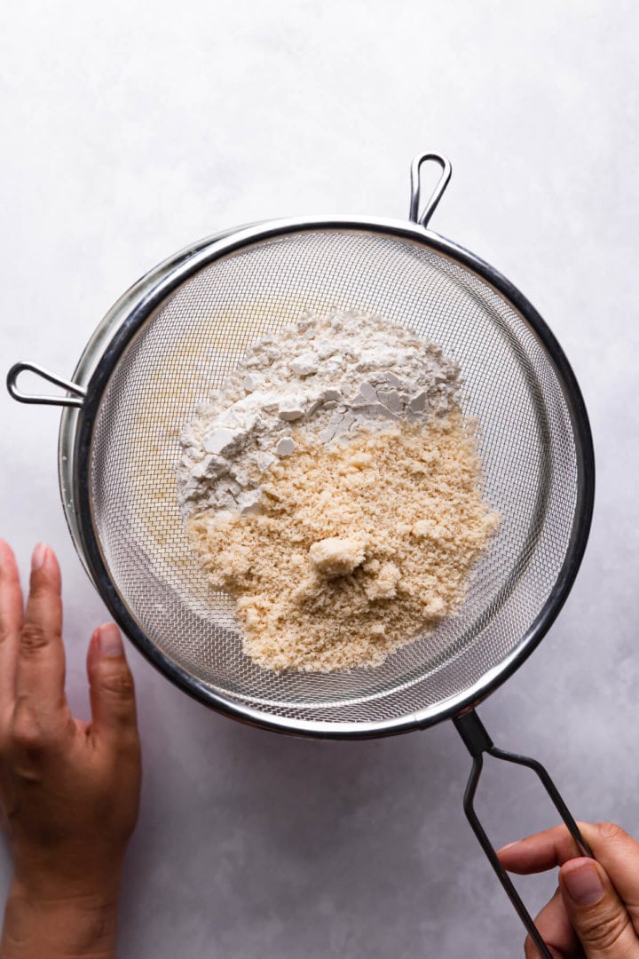 overhead view of a person sieving flour into bowl