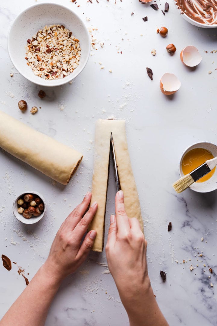 top view of a person slicing rolled dough into half