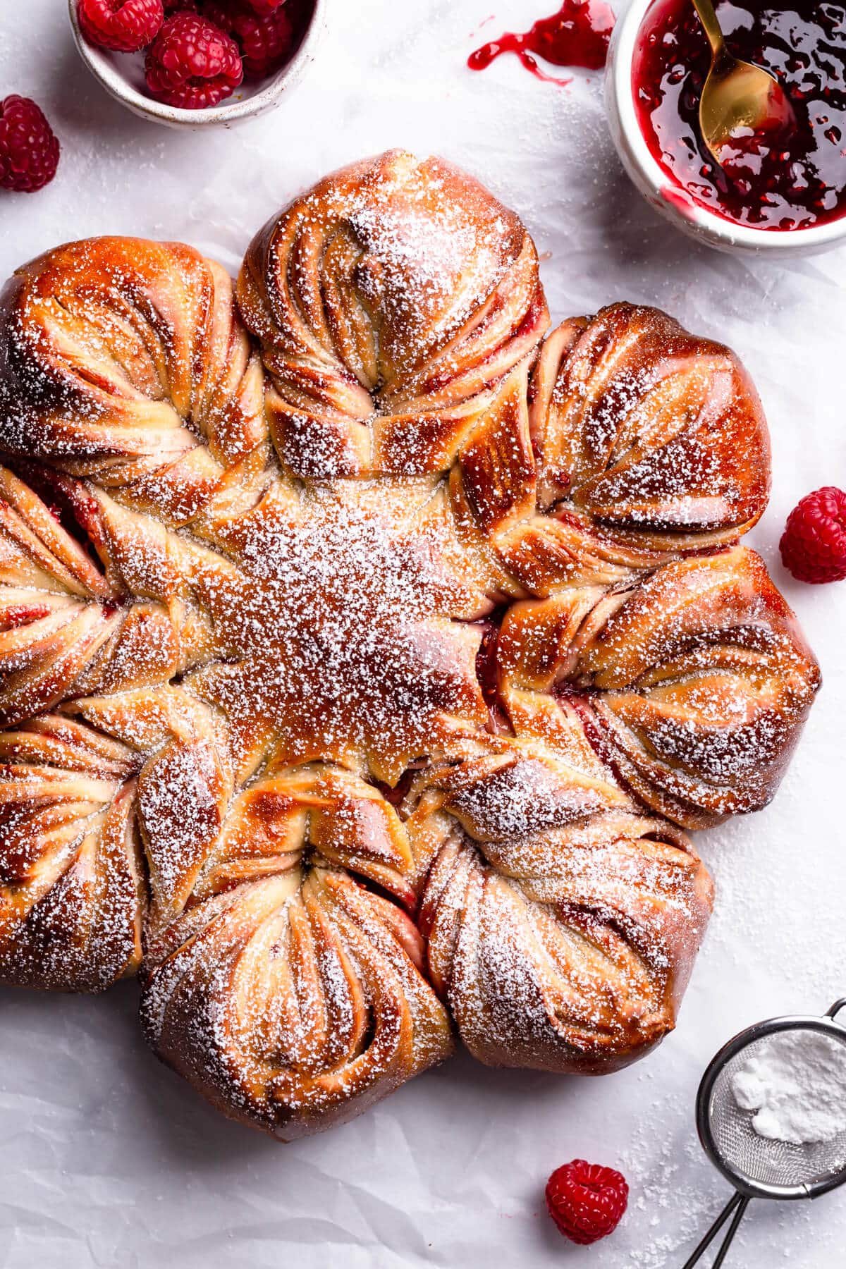 overhead close up at a raspberry star bread with icing sugar on top