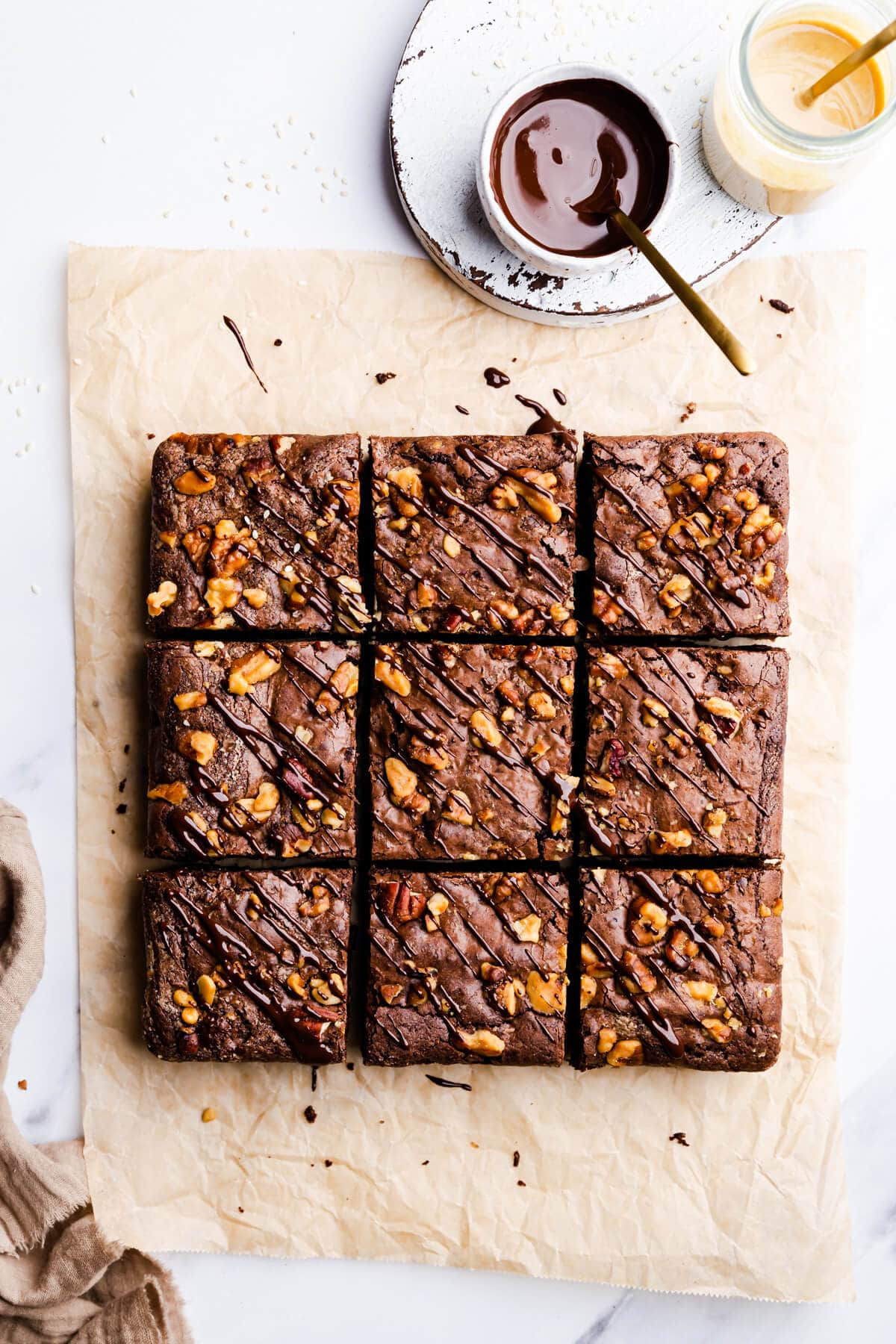 overhead view of 9 square slices of tahini and chocolate brownies with chocolate tahini drizzle