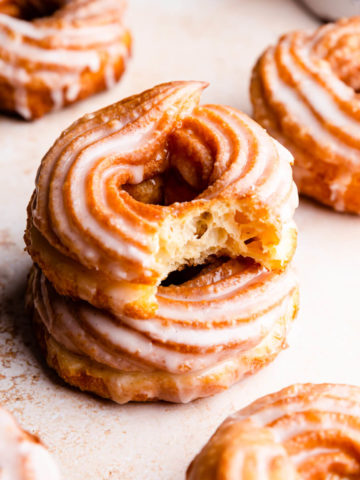 a side close up at a stack of two crullers with the top one missing a bite