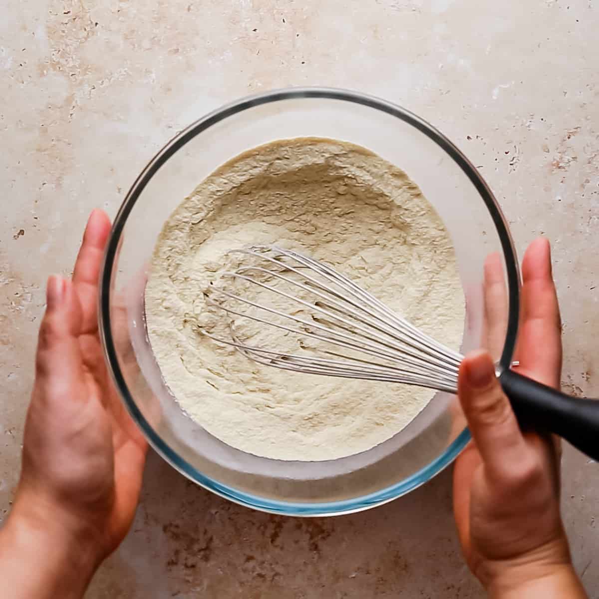 mixing bowl with dry ingredients being combined with kitchen whisk.
