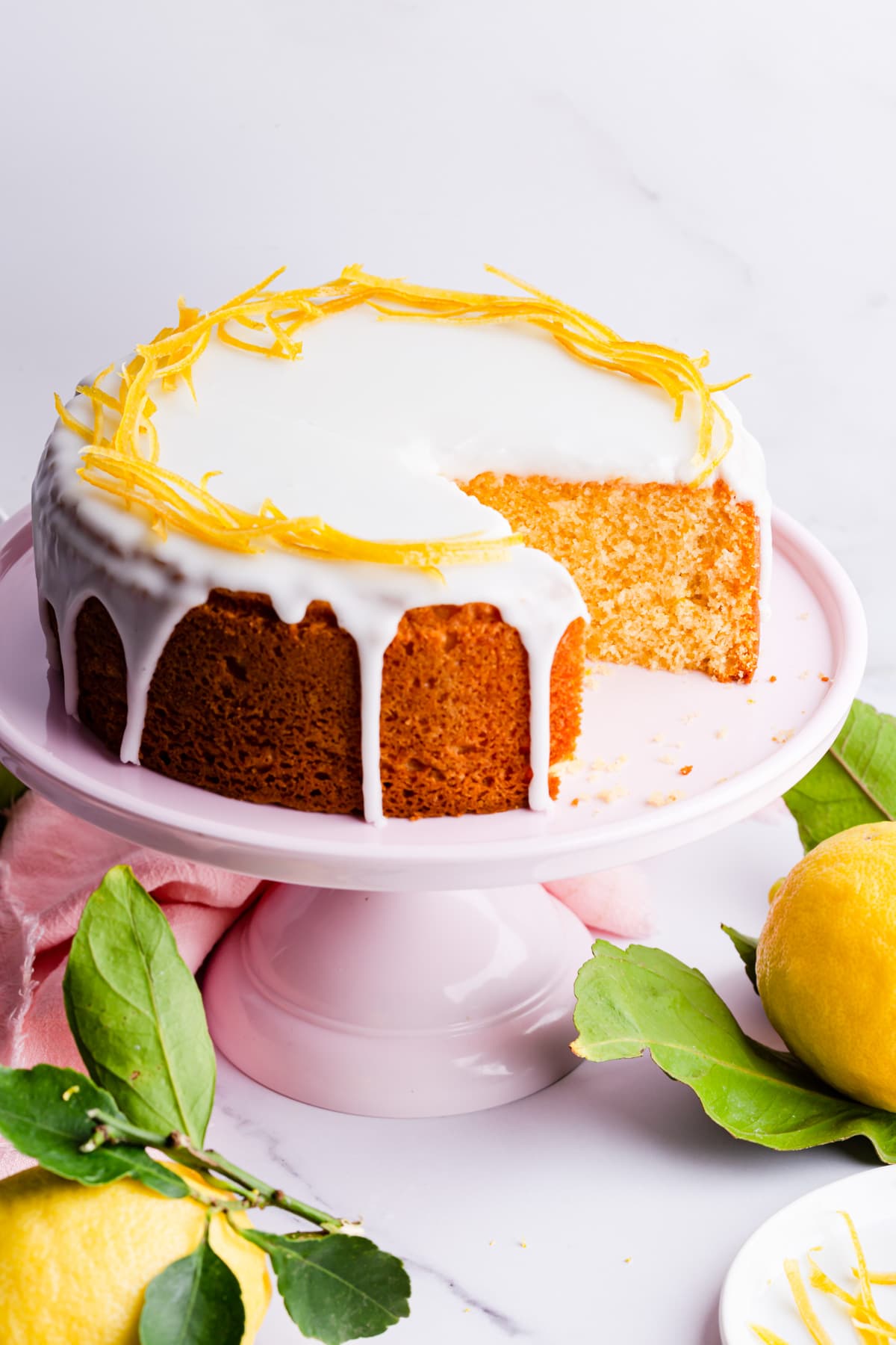citrus cake with icing and a slice cut out of it.