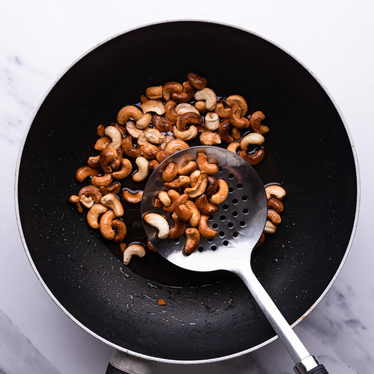 top down view of a wok with fried cashew nuts