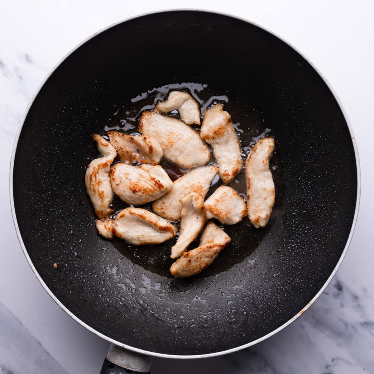 top down view of chicken being fried in the wok pan