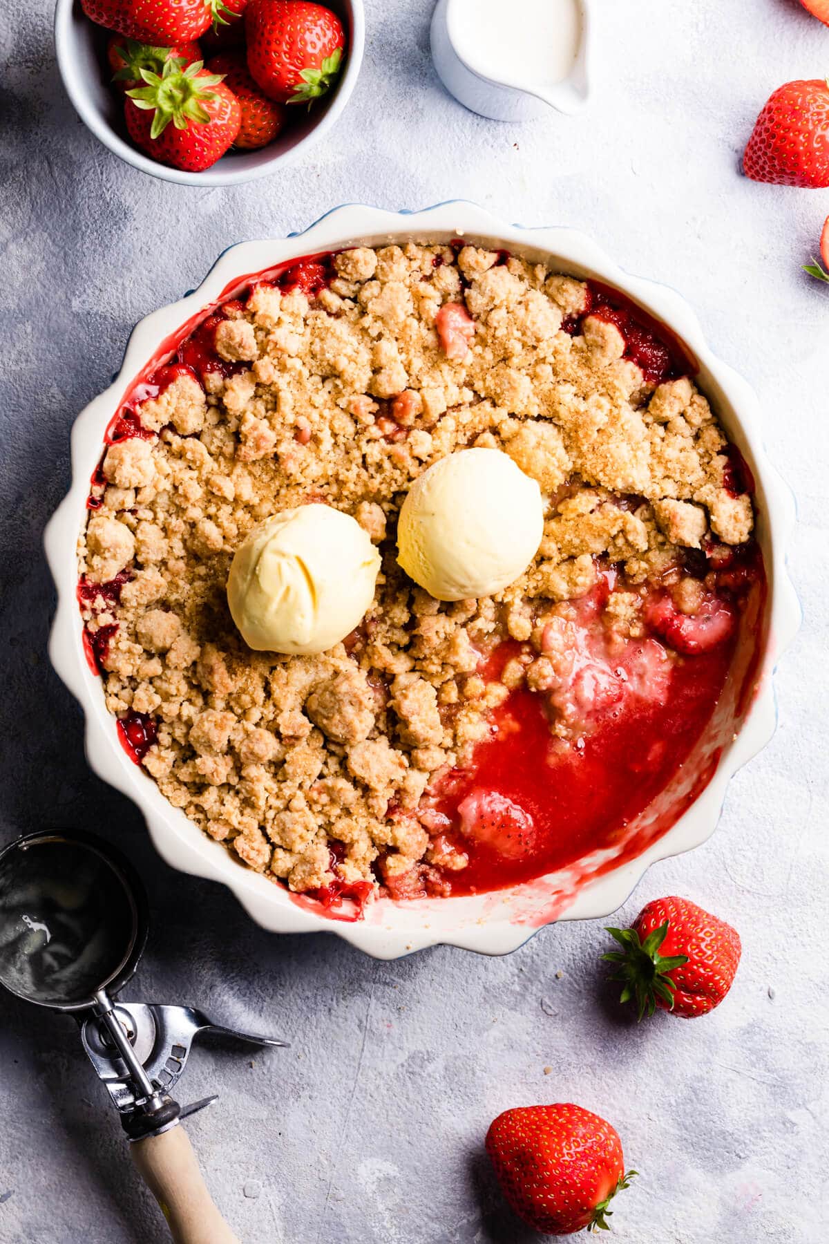 overhead view of a baked strawberry crumble with two scoops of ice cream on top