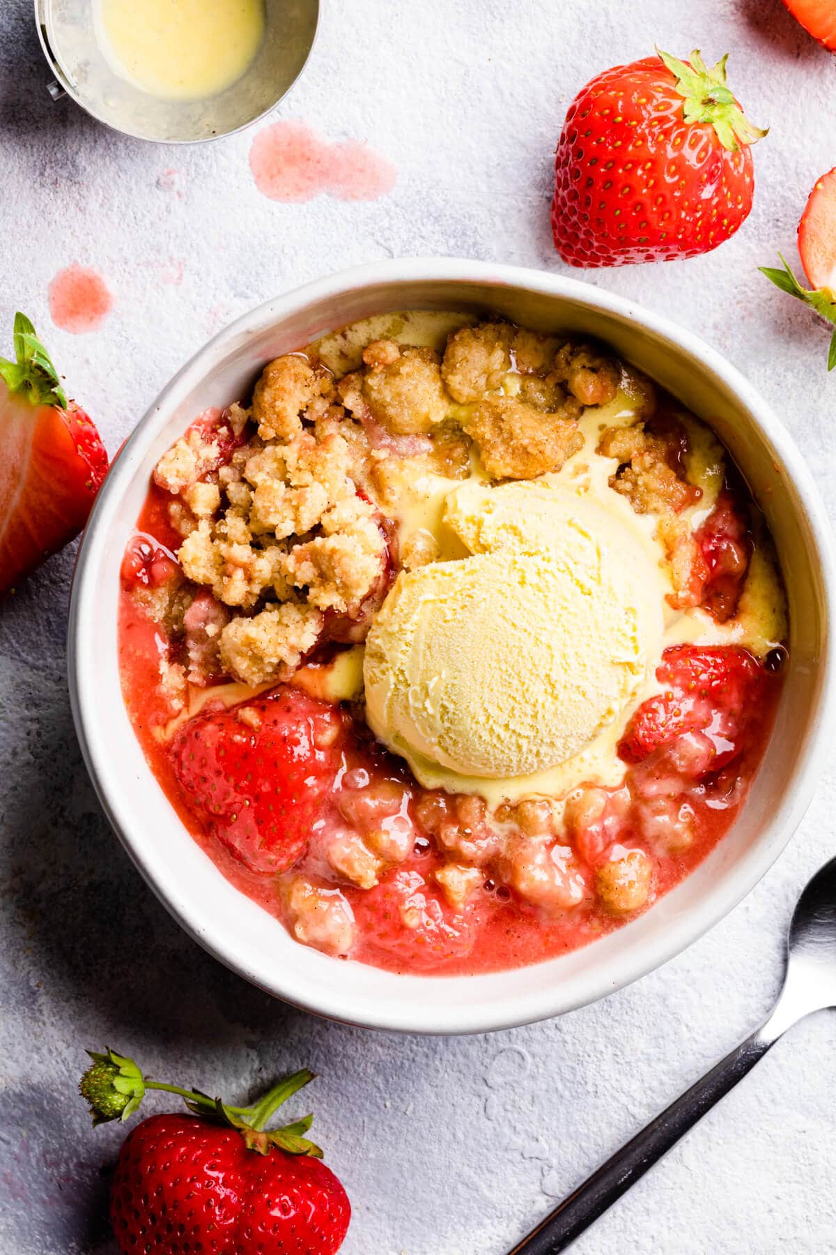 top down view of a bowl with strawberry crumble and a scoop of ice cream