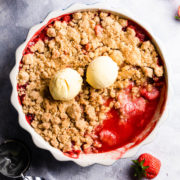 top down view of a strawberry crumble in a baking dish and ice cream on top