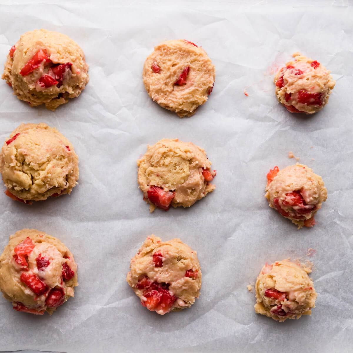 overhead view of cookie dough with strawberries on a baking tray