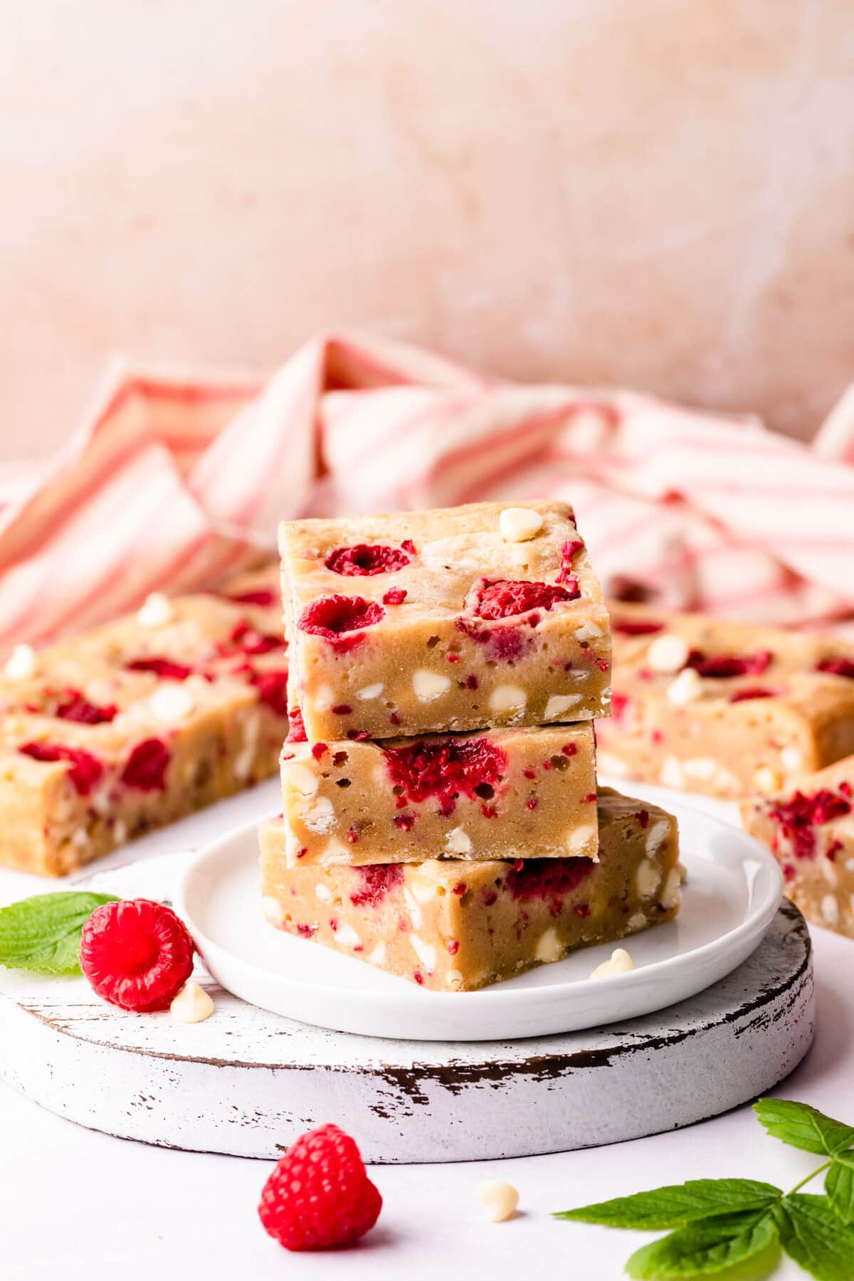 white chocolate and raspberry blondies cut into squares on a small white chopping board.