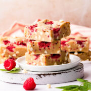 stack of three raspberry blondies with some more blondies in the background.