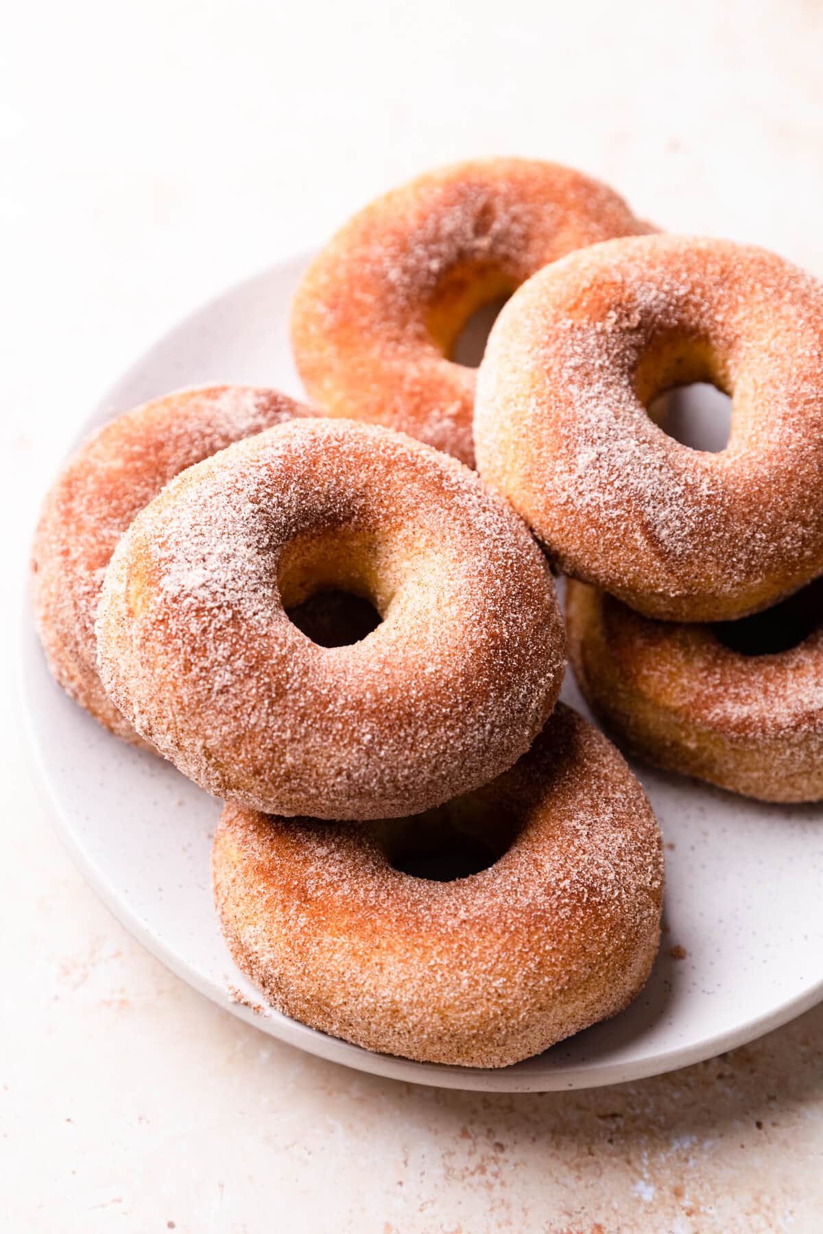 six air fried donuts with cinnamon sugar on a large white plate.