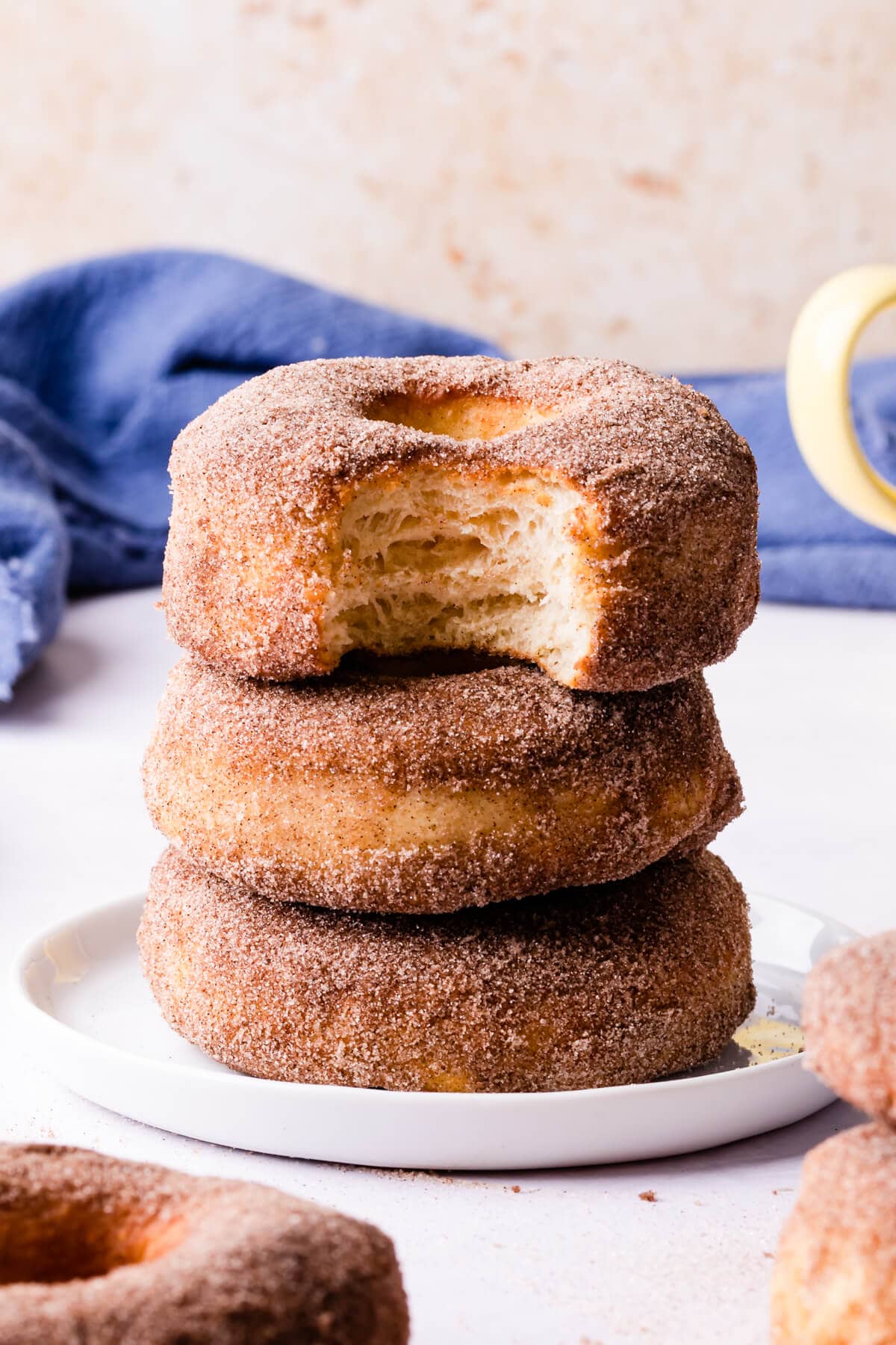 stack of doughnuts on a small white plate with the top doughnut missing a bite.