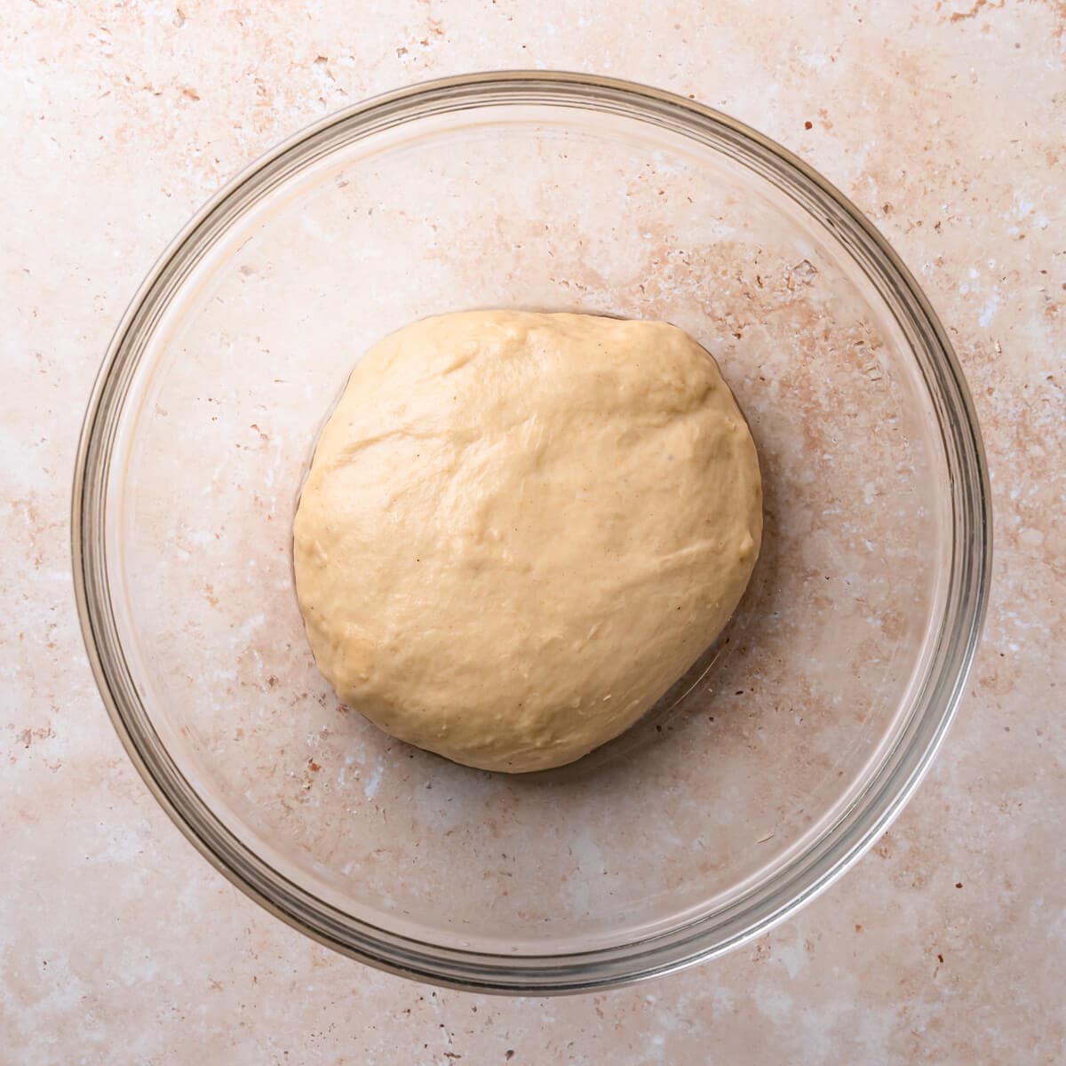 kneaded yeasted dough in a glass bowl.