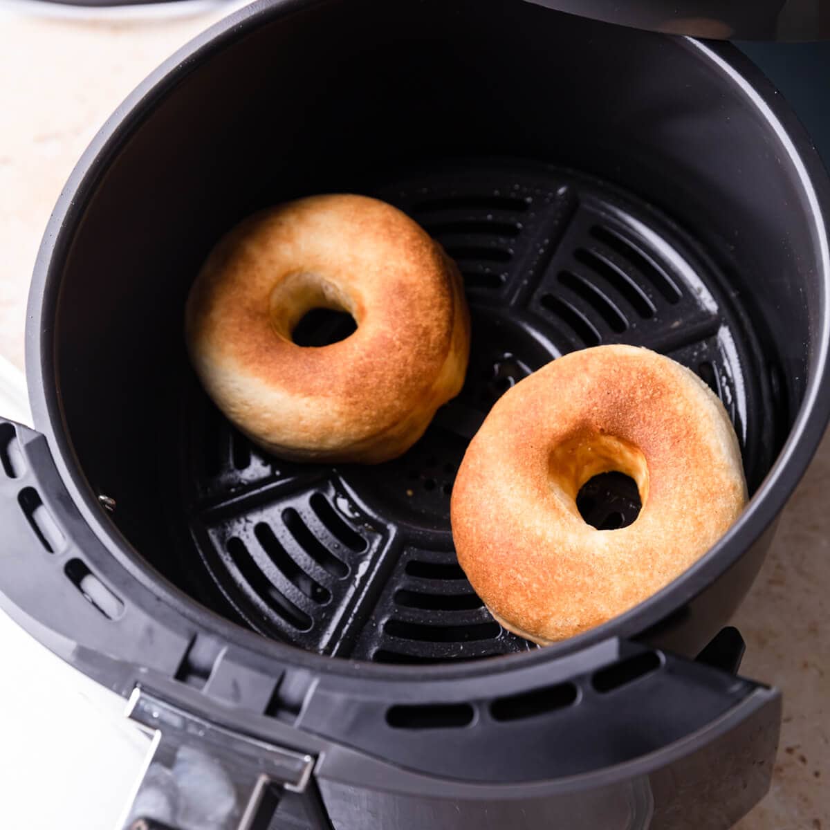 couple of doughnuts in a basket of an air fryer.