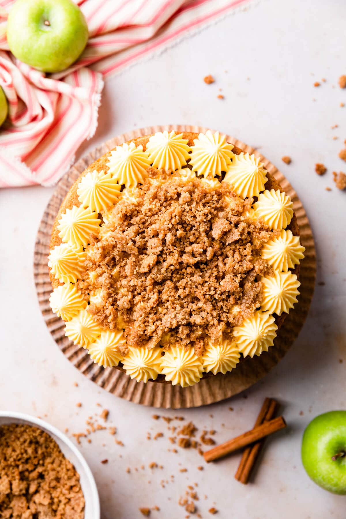 an apple crumble cake with piped buttercream and crumble topping.