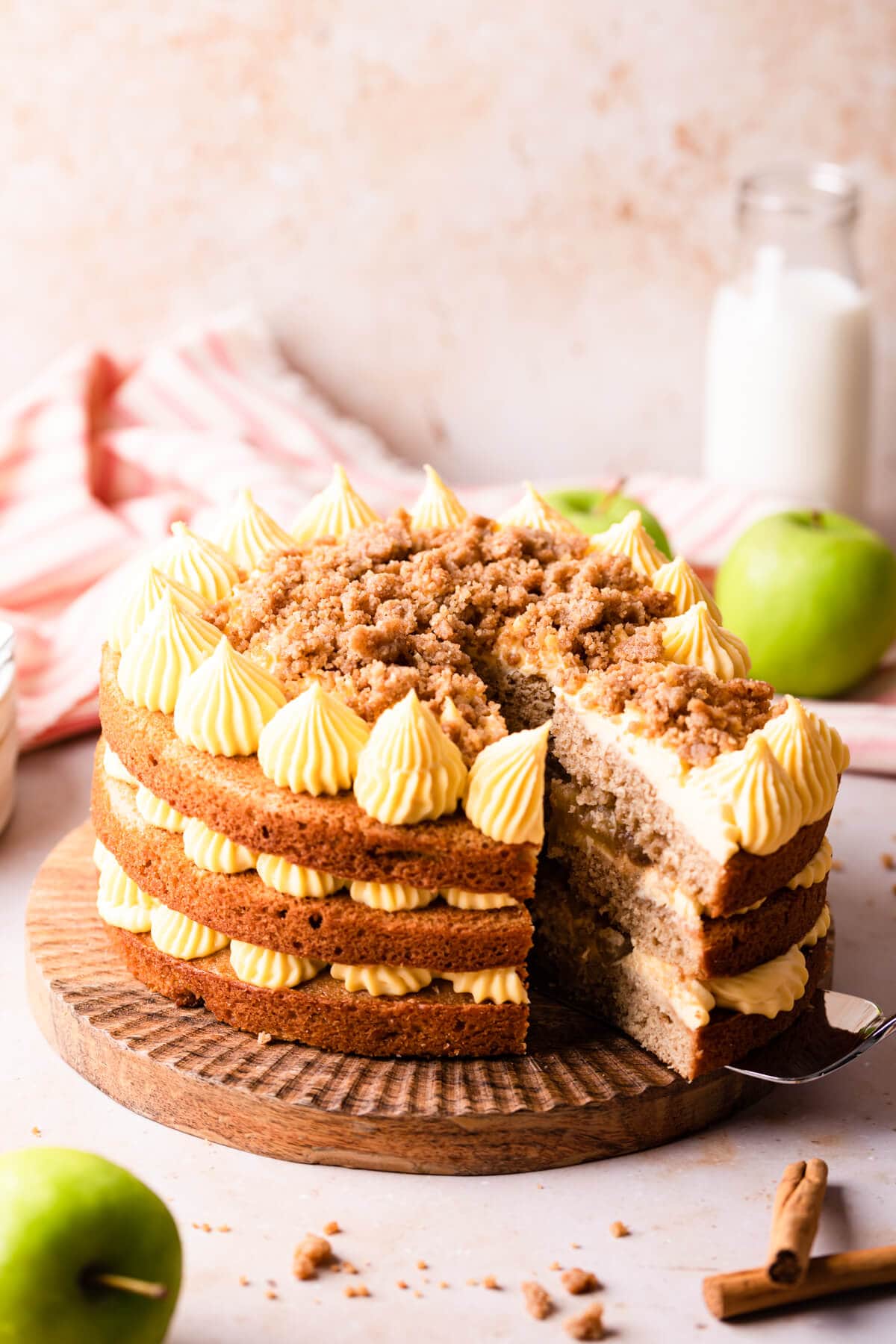 apple cake on a wooden cake stand with a slice being cut out.