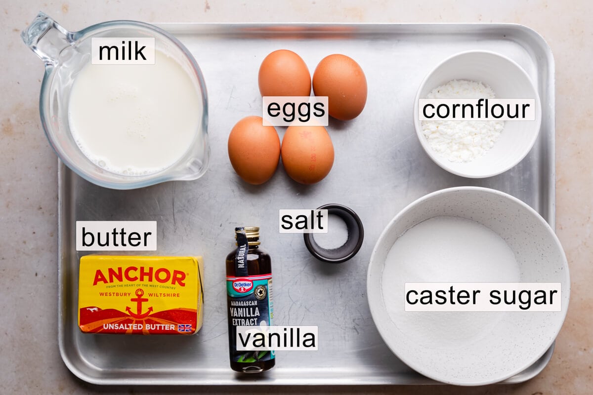 an ingredients to make custard buttercream on a large baking sheet with text labels.