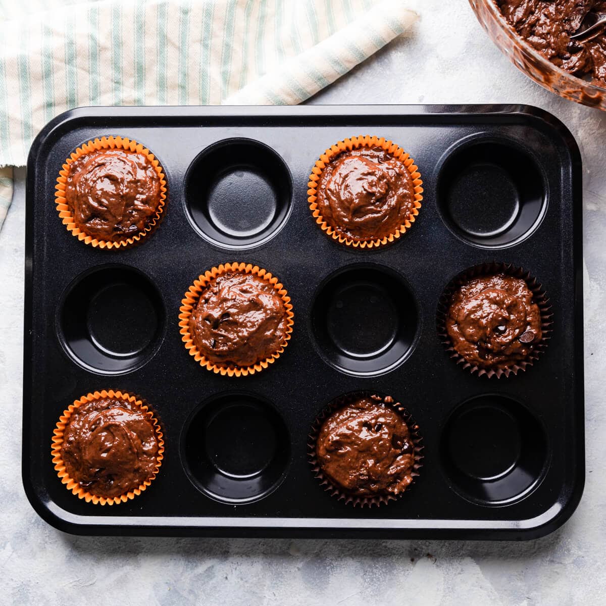 a muffin tin with 6 paper cases filled with muffin batter.