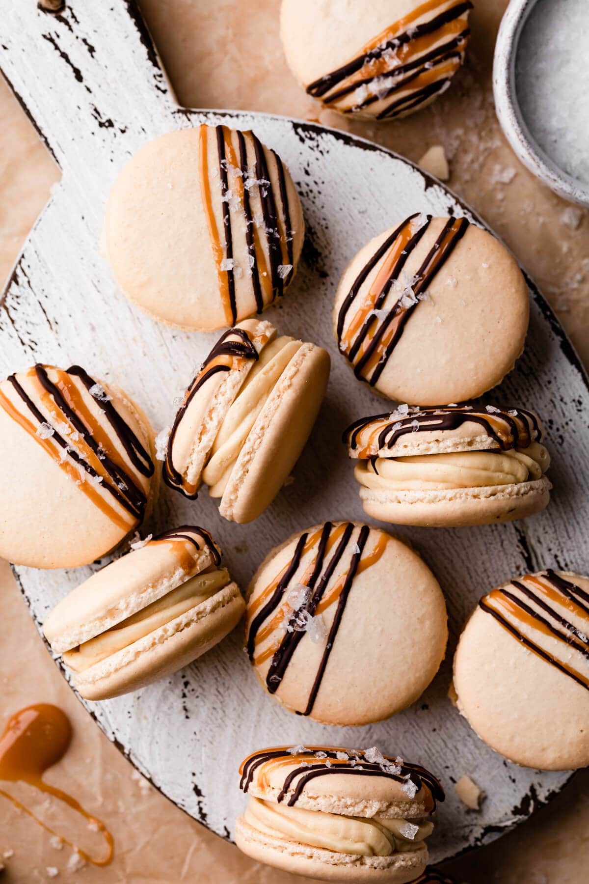 caramel macarons topped with chocolate and caramel drizzle and some sea salt flakes.