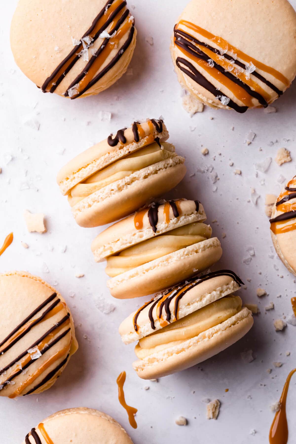 salted caramel macarons with crumbs and sea salt flakes around them.