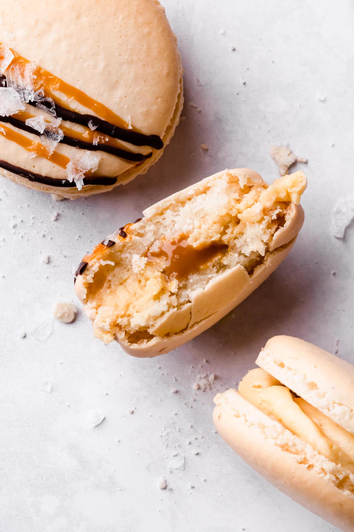 an individual macaron with bite taken out of it filled with caramel and buttercream.