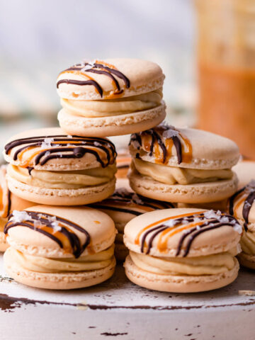 stack of salted caramel macarons on a white wooden board.