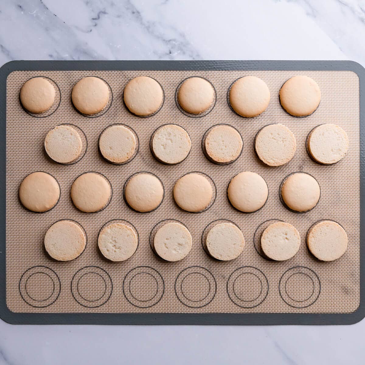 baked macaron top and bottom shells on a silicone baking mat.