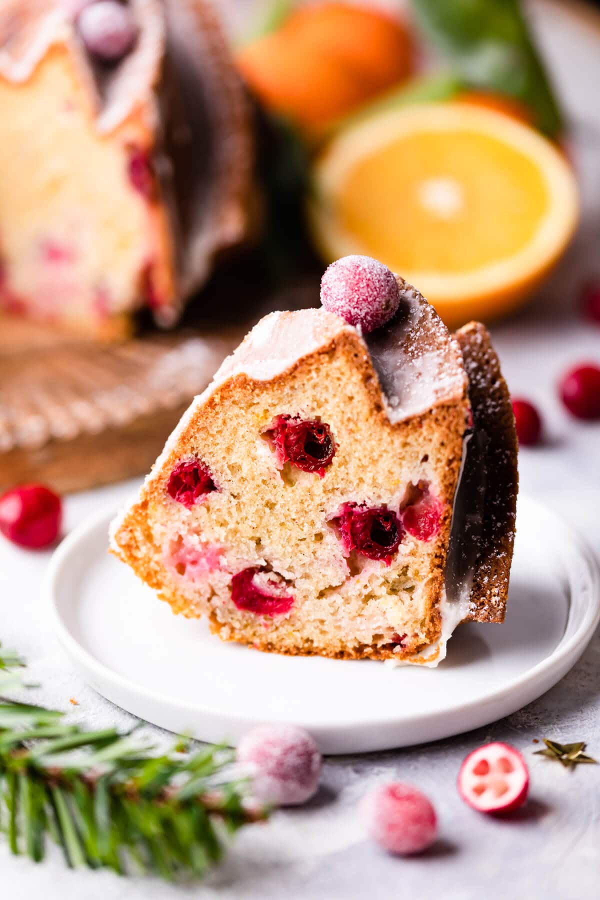 an individual slice of orange and cranberry bundt cake on a small plate.