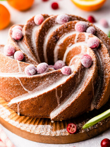 orange cranberry bundt cake with drizzled with glaze and topped with sugared cranberries.