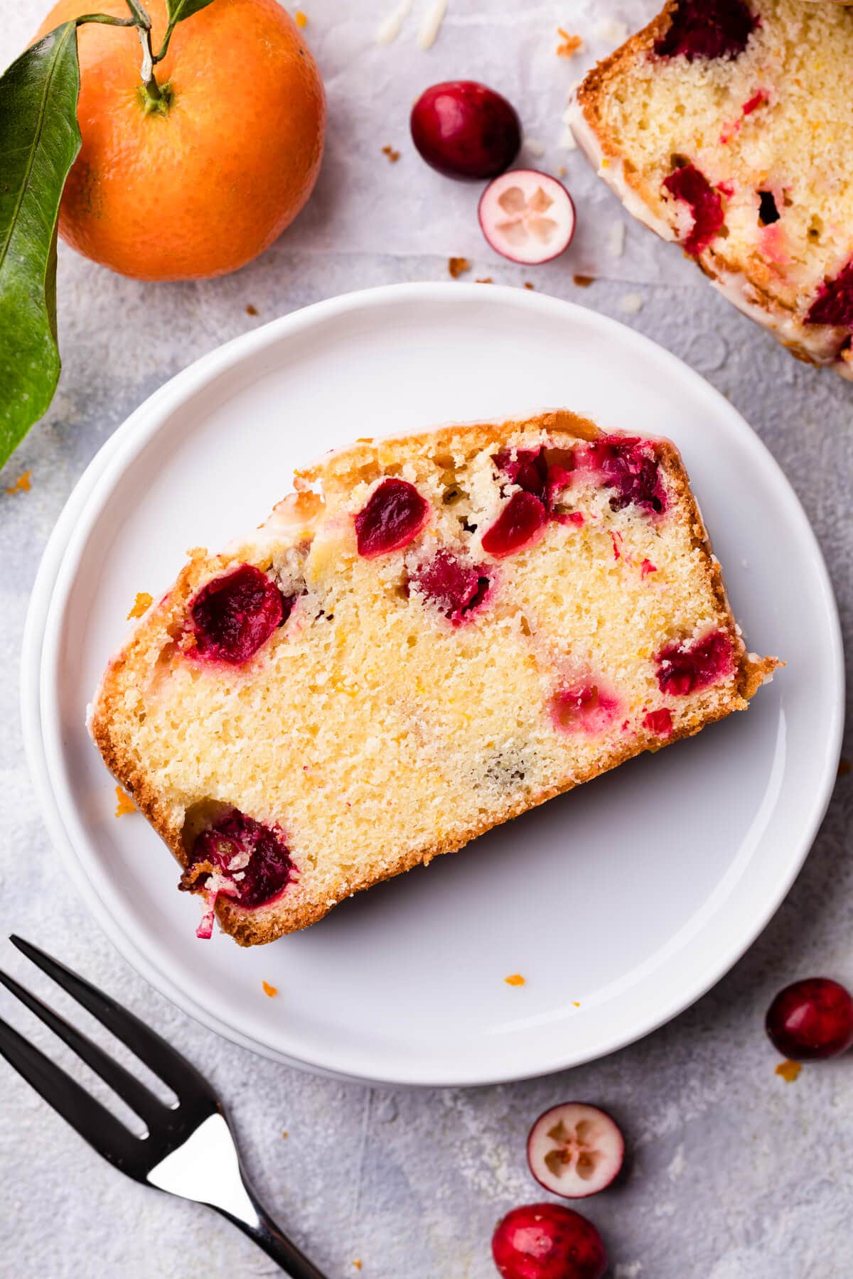 a single slice of the cranberry orange loaf on a white plate.