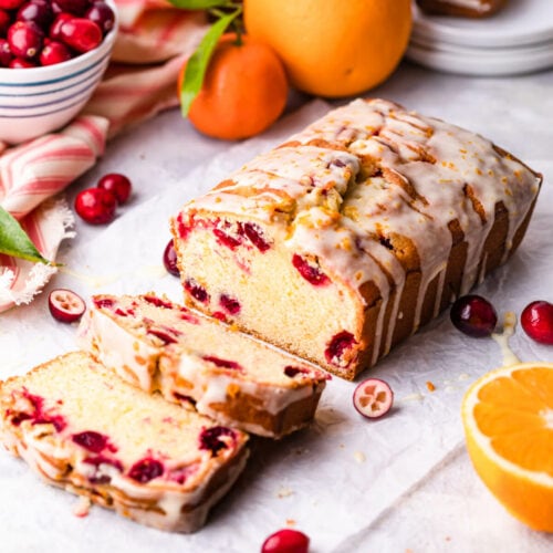 cranberry orange bread with citrus glaze with couple of slices cut off.