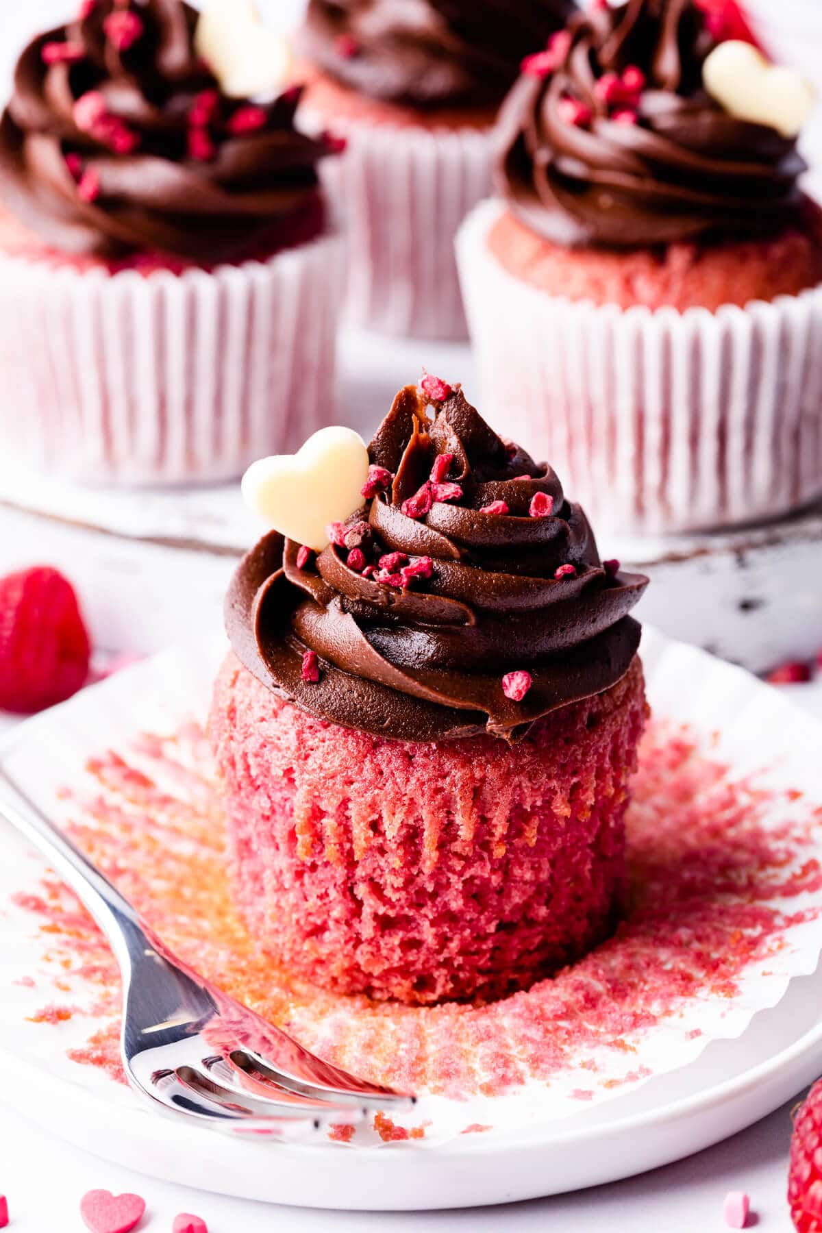an individual chocolate raspberry cupcake on a dessert plate with fork next to it.