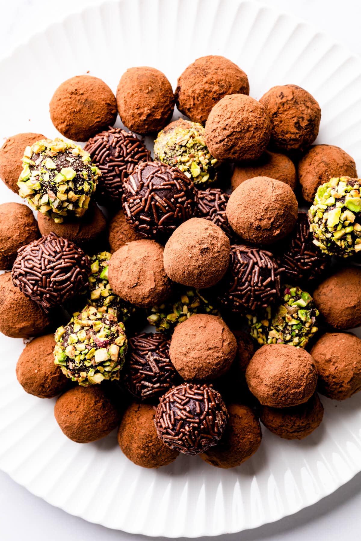 a pile of chocolate truffles on a white plate.