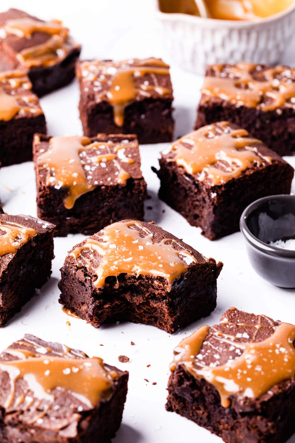 square pieces of brownies drizzled with salted caramel with one brownie missing a bite.
