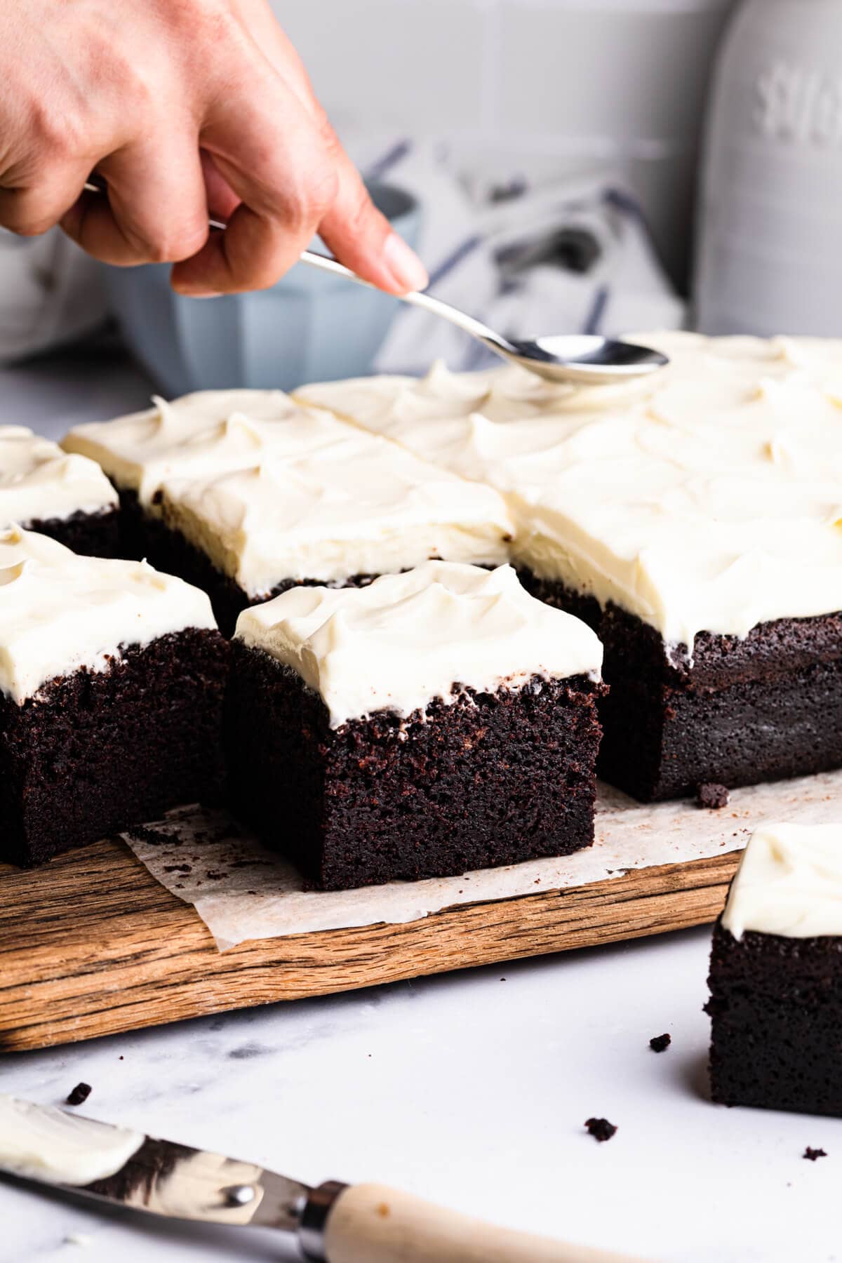Guinness chocolate traybake cake with cream cheese frosting on a wooden chopping board.