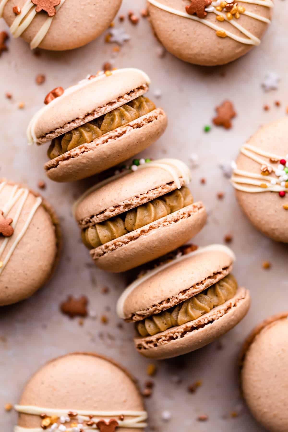 three macarons filled with buttercream on a flat surface with sprinkles around them.