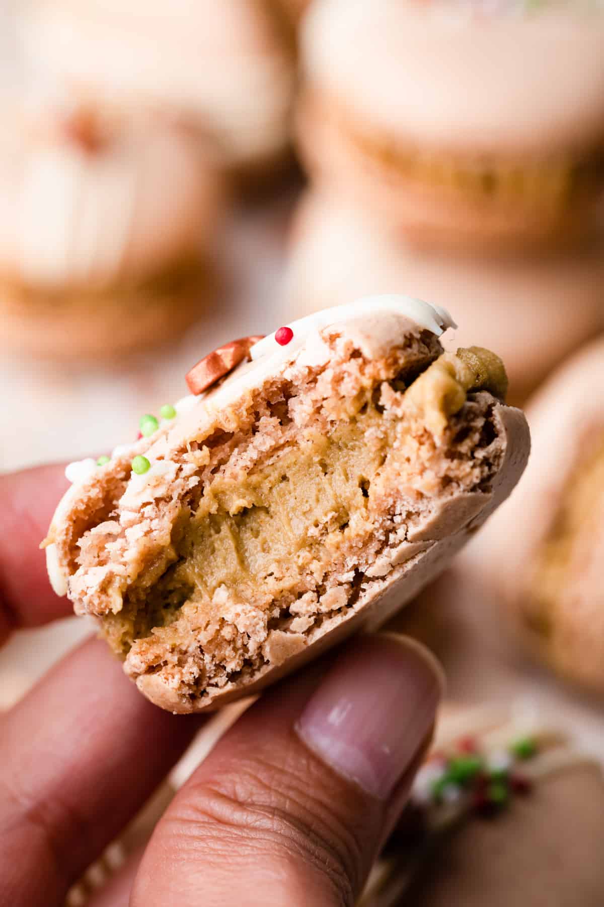 festive macaron with bite taken out of it showing gingerbread buttercream filling.