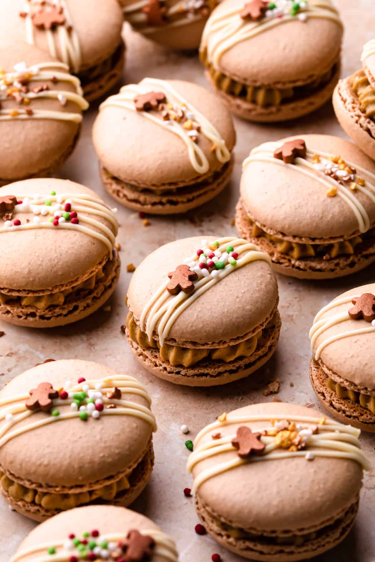 Christmas gingerbread macarons drizzled with white chocolate and sprinkles on top.